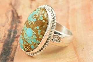 Genuine Number 8 Turquoise set in Sterling Silver Ring. The Number 8 mine is located in Eureka County Nevada. Since 1976 there has been no Number 8 Turquoise mined. There is however, an existing stock pile that Mr. Dowell Ward, the last owner of the Number 8 mine, had stocked away for later sorting. The Turquoise is a collector's item--because once the reserve is gone there will be no more material released onto the market. The Gold Mining Company owns the claim to the Number 8 mine and it has been swallowed up by the gold mining operations. This is some of the last Number 8 Turquoise to be had and will be a great addition to your collection. Created by Navajo Artist Phillip Sanchez.
